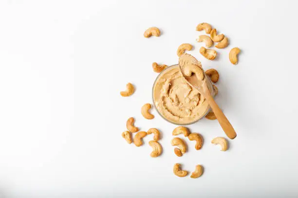 Jar of cashew butter with cashew nuts on the white  background