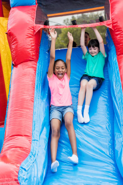 dwie dziewczyny bawiące się na gigantycznej dmuchanej zjeżdżalni - inflatable slide sliding child zdjęcia i obrazy z banku zdjęć