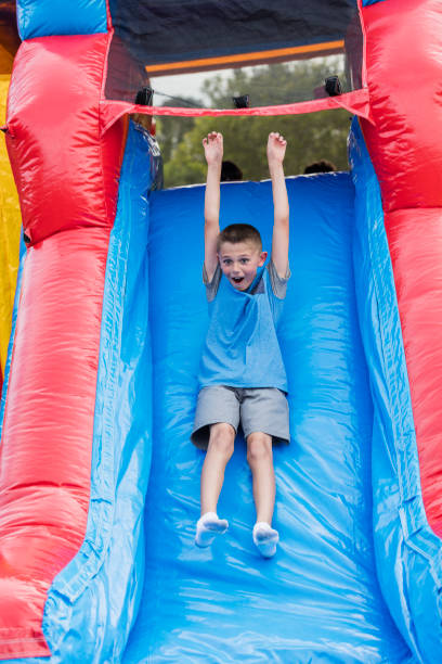 istock Boy sliding down giant inflatable slide 1305387146