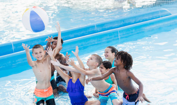 istock Children in pool reaching up to catch a ball 1305387799