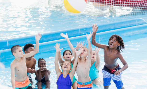 istock Children in pool reaching up to catch a ball 1305388364