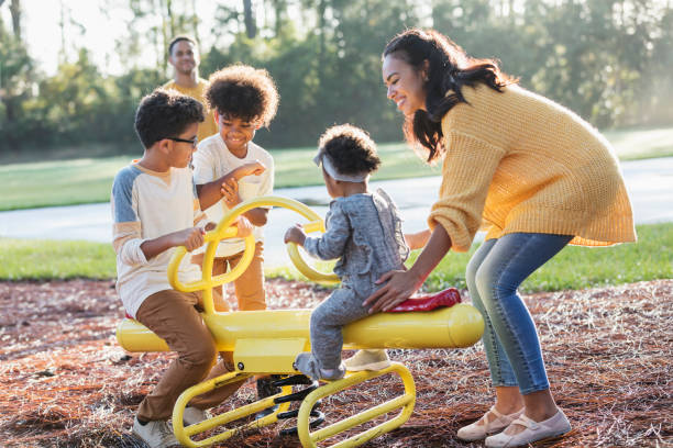 familia de raza mixta en el patio de recreo en veesaw - familia con tres hijos fotografías e imágenes de stock