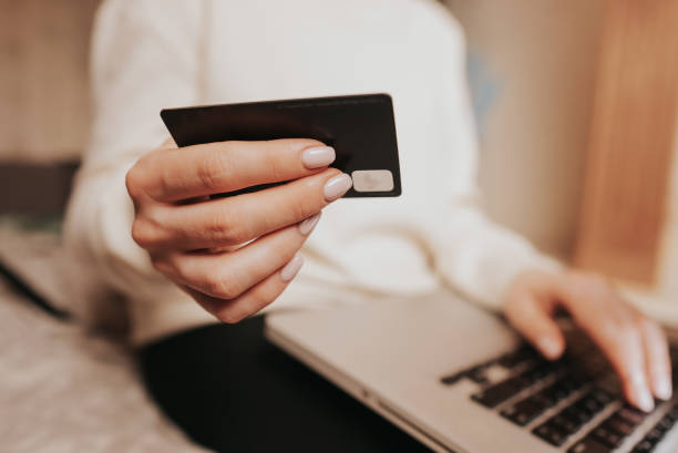 istock Unrecognizable woman holding credit card and using laptop computer while online shopping. Businesswoman working from home. Internet banking, money transfers concept. 1305389496