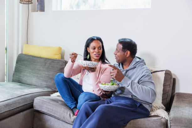 istock Mature couple sitting on sofa with lunch, watching tv 1305390632