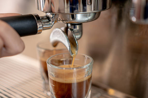 istock Grey coffee machine with two cups filled with coffee on a metal grid in close up concept. 1305398544