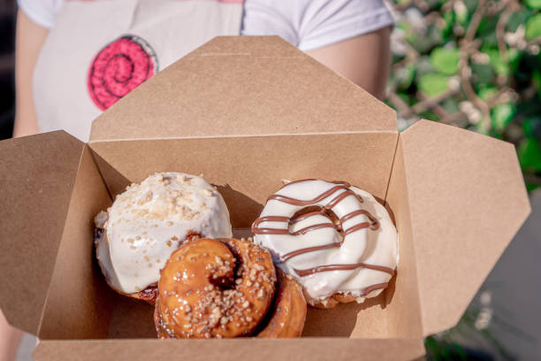 istock Delicious cinnamon rolls glazed and decorated inside a box held by a woman. 1305398852