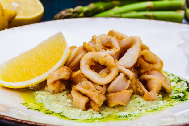 istock Deep fried squid rings or calamari with sauce and lemon on white plate. 1305399705