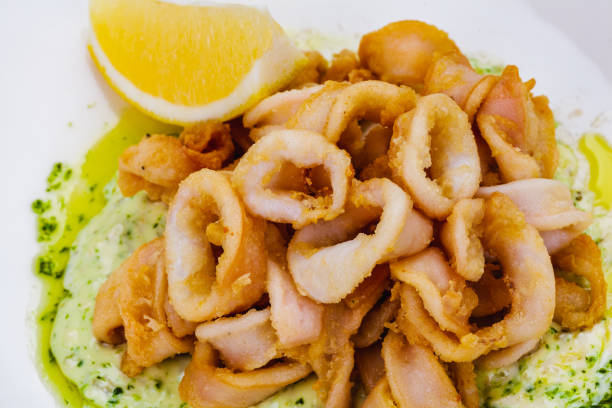 istock Deep fried squid rings or calamari with sauce and lemon on white plate. 1305399708