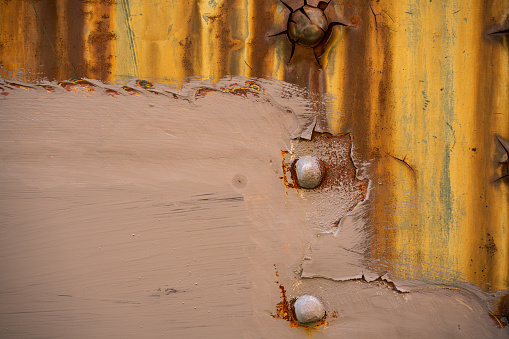 A horizontal color photograph of an actual aged and severely rusted metal wall with copy area photographed outdoors.