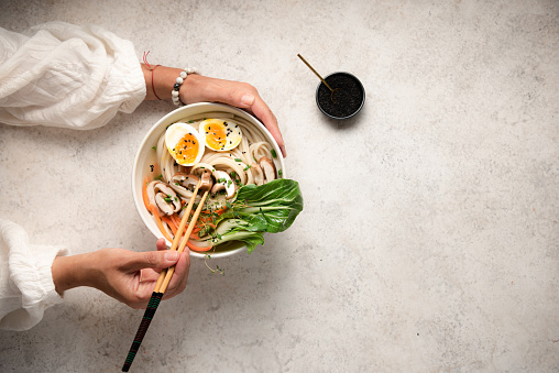 Flat lay of noodle bowls with hands