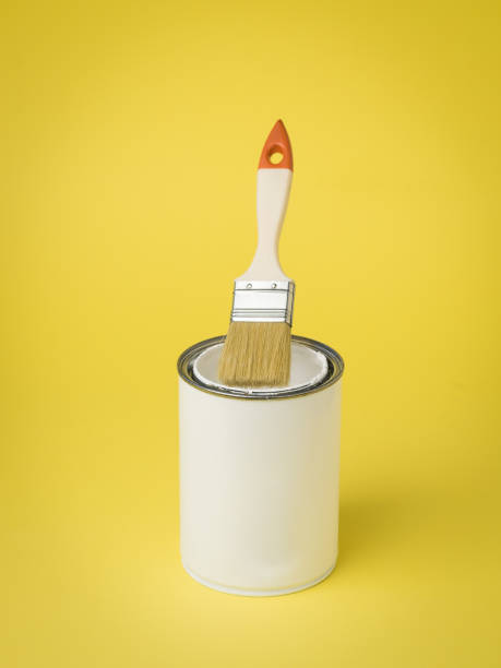 istock Brush over a jar of open paint on a yellow background. 1305415217