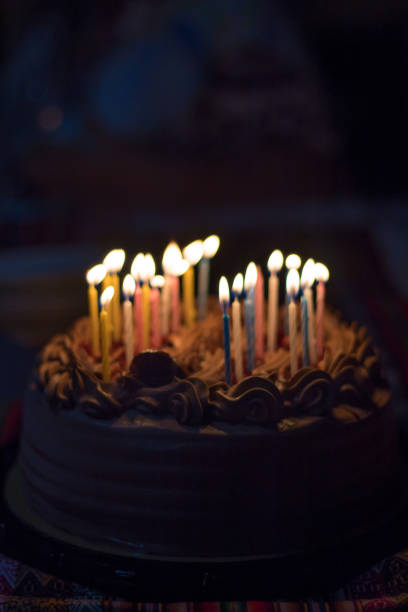 istock Sweet Birthday cake on a table with colors candles lighted 1305416099