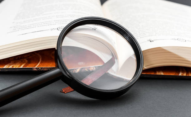 istock Magnifying glass with opened book on black. Close up. 1305420416