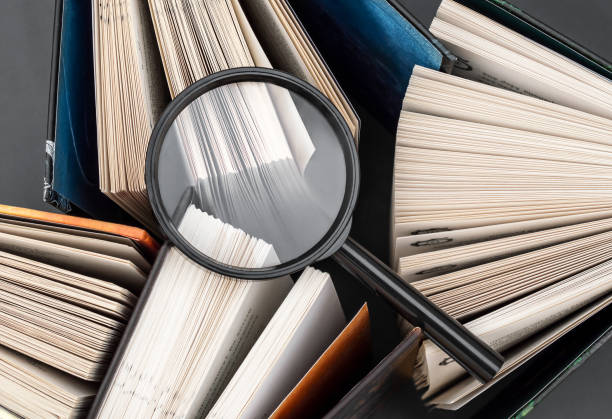 istock Magnifying glass on books. Top view. Learning, study and search information. 1305420438