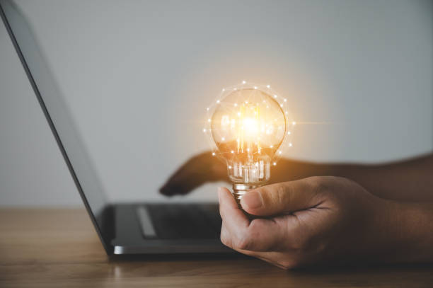 istock Hand holding light bulb and working on computer laptop. Concept of inspiration creative idea thinking and future technology innovation 1305427856