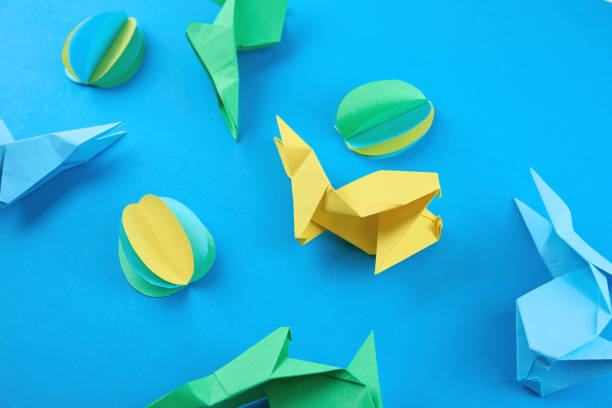 istock Paper origami Esater rabbits and colored eggs on blue background. Easter celebration concept 1305428673