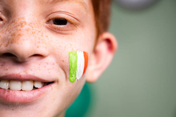 close-up de garoto sorridente com saint patricks dia bandeira irlandesa tricolor no rosto das crianças durante a celebração do festival wih espaço de cópia - republic of ireland flag human face irish culture - fotografias e filmes do acervo