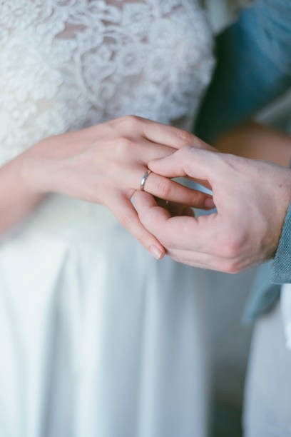 istock wedding ring on the finger. The groom puts the ring on the bride. wedding 1305433437