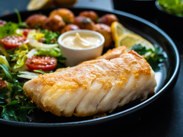istock Fried cod fillet with fried potatoes and fresh vegetables 1305434916