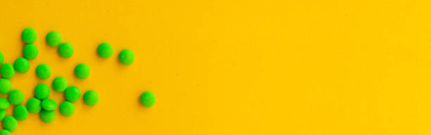 istock banner, green vitamins, pills on a yellow background. 1305437965