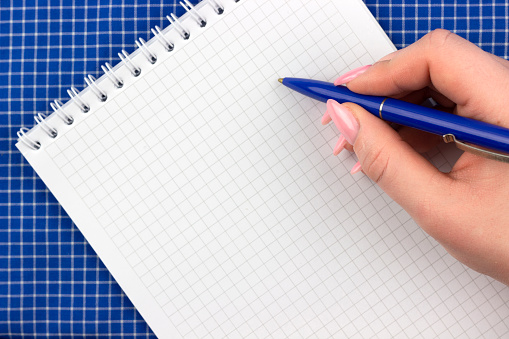 woman makes notes with pen in diary or notepad, hand with notepad close-up