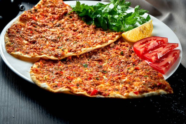 istock Lahmacun is a popular Turkish dish. Thin crispy tortilla with minced lamb, tomatoes and bell pepper on black background 1305440096