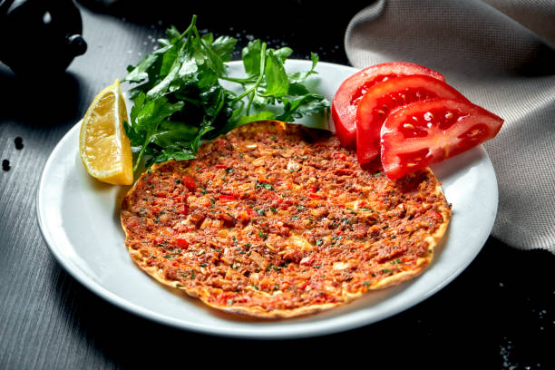istock Lahmacun is a popular Turkish dish. Thin crispy tortilla with minced lamb, tomatoes and bell pepper on black background 1305440150