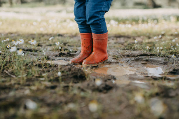 istock Low Section Of Child Standing In Puddle With Red Rubber Boots 1305441929