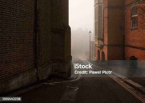 istock Foggy road between buildings of Harrow on the Hill in England 1305442238