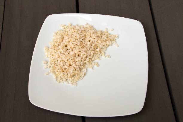 ein teller mit gekochtem braunem reis. - brown rice cooked rice steamed stock-fotos und bilder