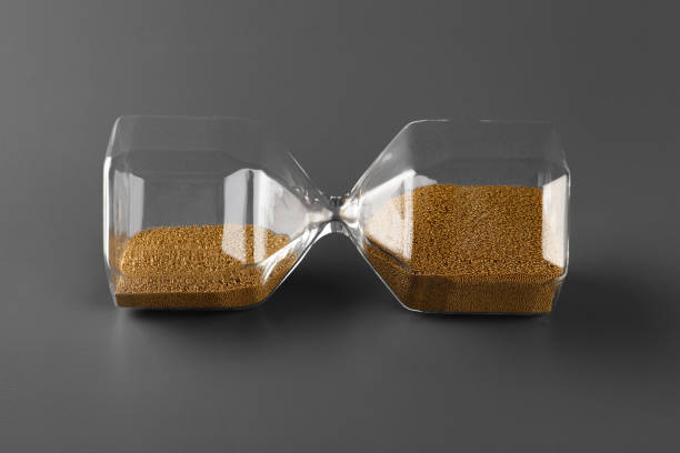 istock Hourglass with sand on gray background close up 1305446277
