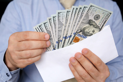 Dólares estadounidenses en manos masculinas de cerca, hombre vestido de negocios con dinero en sobre blanco photo