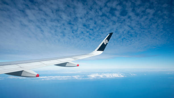 Aerial view of an airplane wing with Air New Zealand logo on it. Blue sky with fluffy white clouds in the sky and blue sea underneath. Image taken on Air NZ flight flying from Auckland to Queenstown Aerial view of an airplane wing with Air New Zealand logo on it. Blue sky with fluffy white clouds in the sky and blue sea underneath. Image taken on Air NZ flight flying from Auckland to Queenstown window seat vehicle stock pictures, royalty-free photos & images