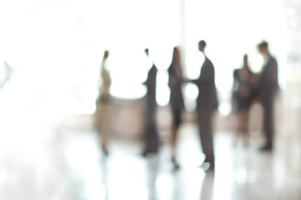 blurry image of a group of business people standing in the office lobby stock photo