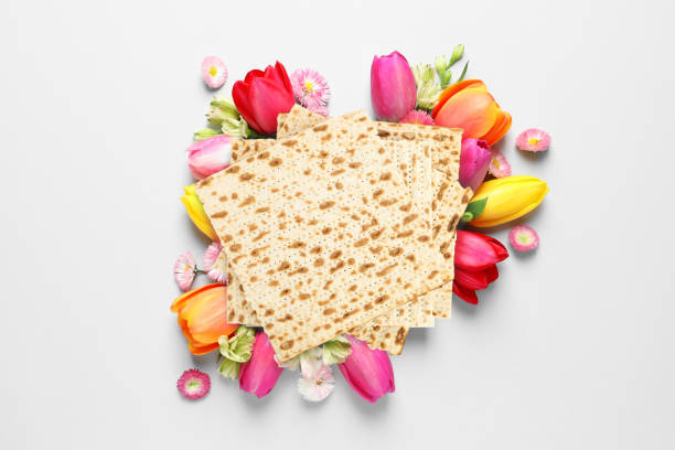 istock Tasty matzos and flowers on light background, flat lay. Passover (Pesach) celebration 1305450540