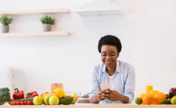 istock Black Woman Using Phone With Cooking Application Preparing Dinner Indoor 1305453026