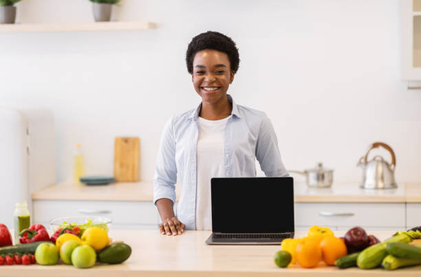 istock Black Lady Posing With Laptop With Blank Screen In Kitchen 1305453182