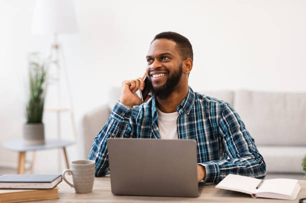istock Cheerful Black Male Entrepreneur Talking On Cellphone Sitting At Workplace 1305453869