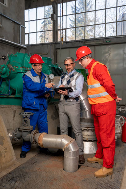 istock Technical Manager with Digital Tablet Talking to Factory Workers in Mechanical Room 1305453901