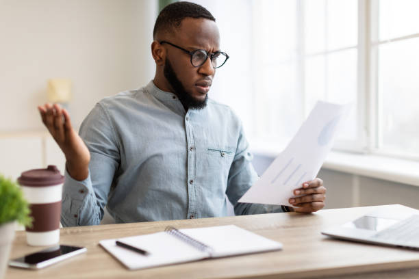 istock Shocked Black Businessman Looking Through Papers Working Sitting In Office 1305453988