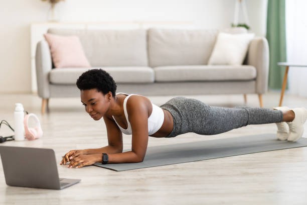 istock African Lady Standing In Plank Position Exercising At Laptop Indoor 1305455212