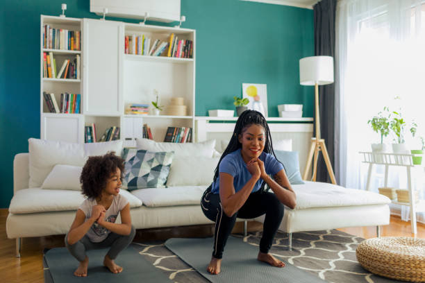 Full-Body Workout High intense training. African woman and her daughter doing burpee at home during coronavirus lockdown. burpee stock pictures, royalty-free photos & images