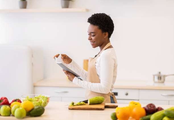 istock Woman Reading Cooking Book Searching Recipe For Dinner In Kitchen 1305458012