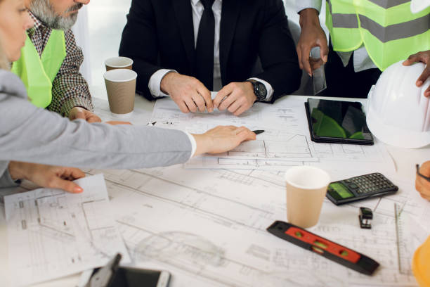 istock Architects, engineers and designers, sitting at the table, analysing blueprints 1305462861