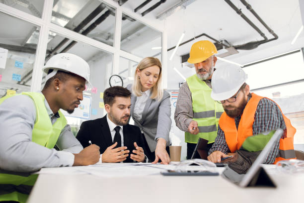 istock Multiracial team of engineers or architects, brainstorming together over joint building project 1305463579