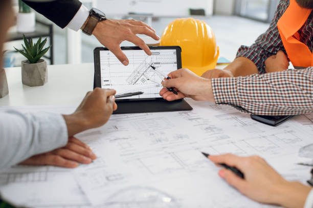 istock Close up of construction team analysing blueprints on tablet 1305463622
