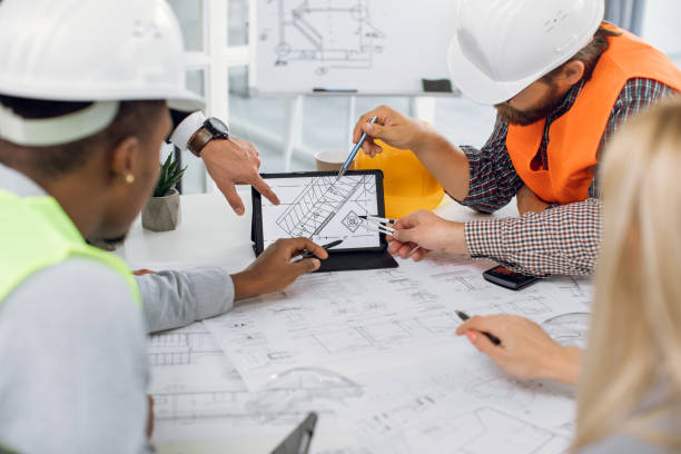 istock Close up of construction team analysing blueprints on tablet 1305463625