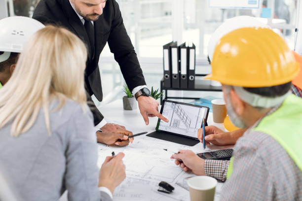 istock Close up of construction team analysing blueprints on tablet 1305463652