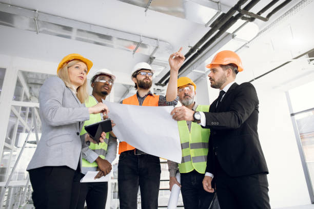 istock Business partners standing on construction with blueprints 1305464314