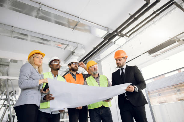 istock Multiracial colleagues in helmets analysing blueprints 1305464324